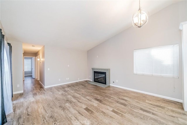 14079 El Camino Pl, Fontana, CA 92337 - unfurnished living room with a brick fireplace, lofted ceiling, light wood finished floors, baseboards, and a chandelier