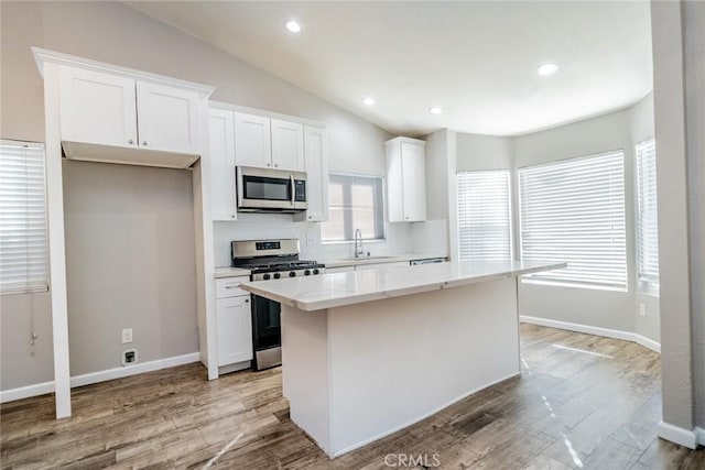 14079 El Camino Pl, Fontana, CA 92337 - kitchen featuring stainless steel appliances, a sink, a center island, vaulted ceiling, and white cabinetry