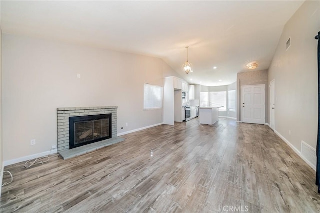 14079 El Camino Pl, Fontana, CA 92337 - unfurnished living room with light wood-style flooring, a brick fireplace, baseboards, and vaulted ceiling