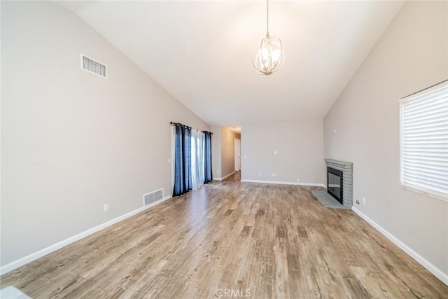 14079 El Camino Pl, Fontana, CA 92337 - unfurnished living room with vaulted ceiling, a brick fireplace, light wood finished floors, a chandelier, and baseboards