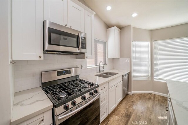 14079 El Camino Pl, Fontana, CA 92337 - kitchen with appliances with stainless steel finishes, a sink, light wood-type flooring, white cabinets, and tasteful backsplash