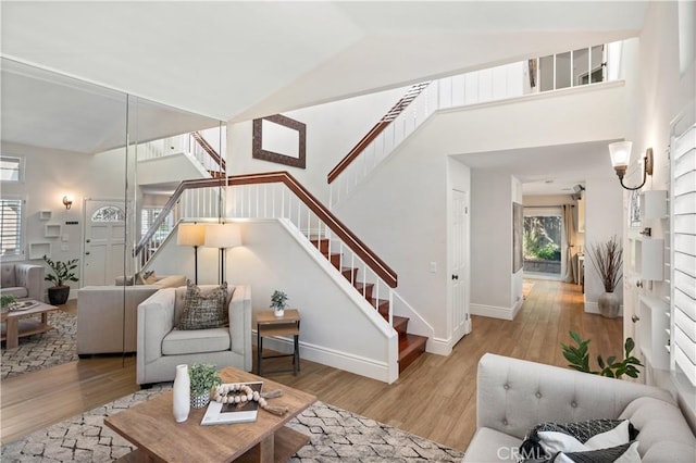 61 Bridgeport, Irvine, CA 92620 - living area featuring stairs, healthy amount of natural light, wood finished floors, high vaulted ceiling, and baseboards