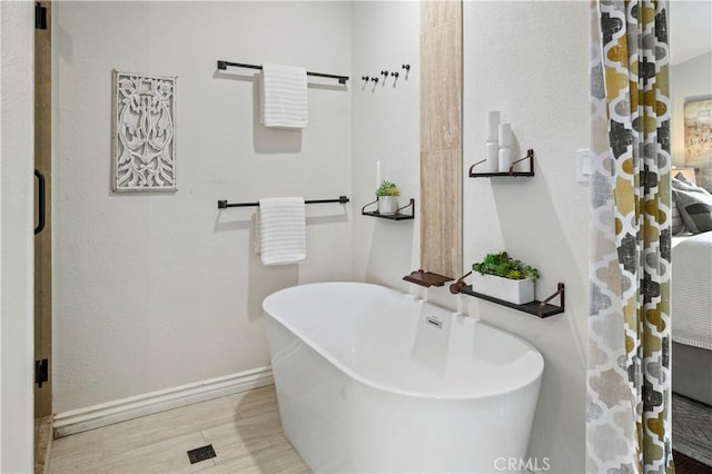 61 Bridgeport, Irvine, CA 92620 - bathroom featuring a freestanding tub, wood finished floors, and baseboards