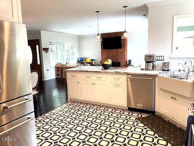 10456 Pomering Rd, Downey, CA 90241 - kitchen with appliances with stainless steel finishes, a peninsula, crown molding, white cabinets, and decorative light fixtures