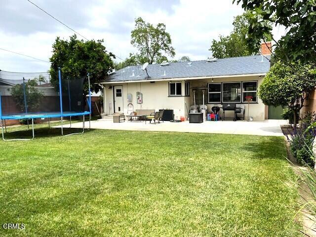 10456 Pomering Rd, Downey, CA 90241 - back of house with a patio area, a trampoline, a yard, and stucco siding