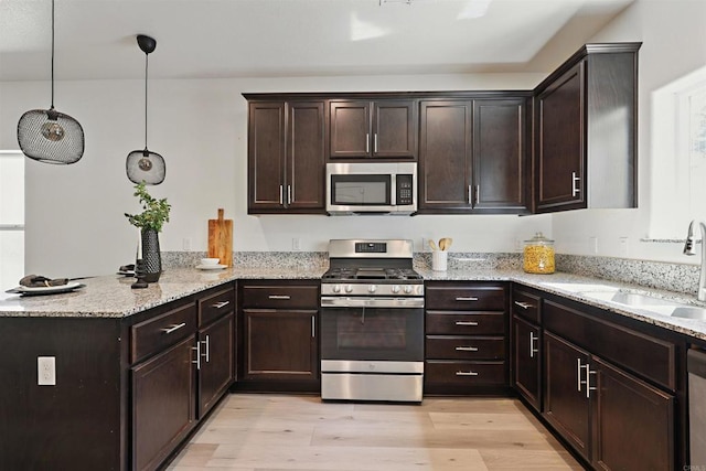 170 Montage Dr, Merced, CA 95348 - kitchen featuring stainless steel appliances, a peninsula, dark brown cabinets, light stone countertops, and light wood finished floors