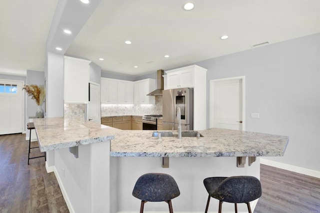 25034 Poderio Dr, Ramona, CA 92065 - kitchen featuring wall chimney exhaust hood, appliances with stainless steel finishes, a breakfast bar area, a peninsula, and recessed lighting