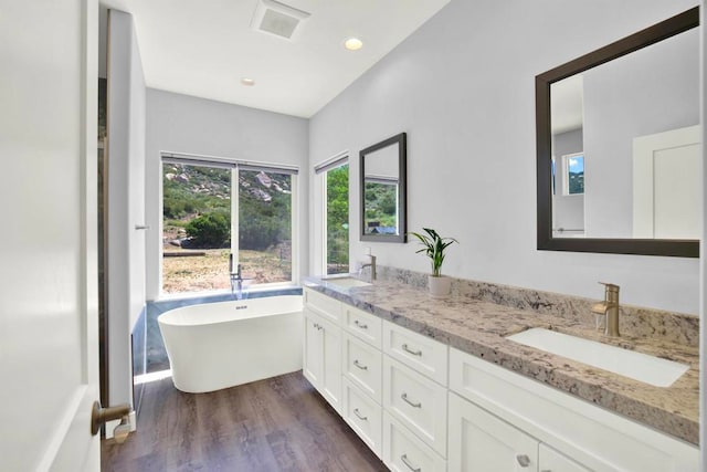 25034 Poderio Dr, Ramona, CA 92065 - bathroom featuring wood finished floors, double vanity, a freestanding tub, and recessed lighting