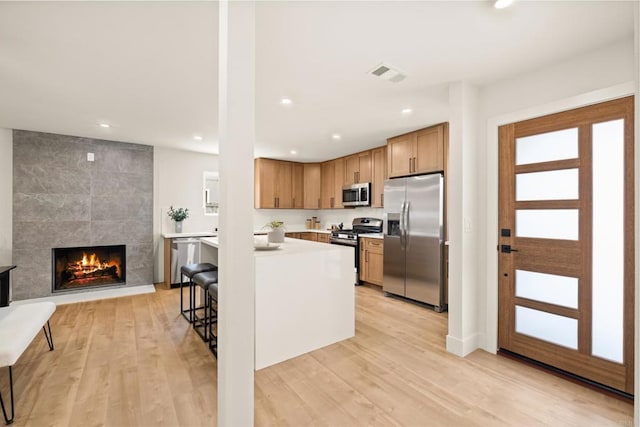 101 Coolwater Dr, San Diego, CA 92114 - kitchen featuring stainless steel appliances, light countertops, recessed lighting, light wood-type flooring, and a fireplace