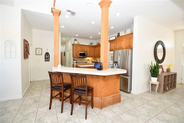 8250 Cataba Rd, Oak Hills, CA 92344 - kitchen featuring ornate columns, stainless steel appliances, a kitchen bar, light countertops, and recessed lighting