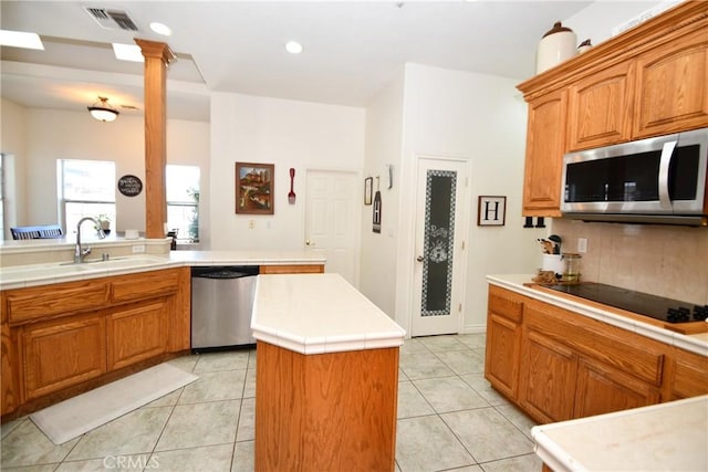 8250 Cataba Rd, Oak Hills, CA 92344 - kitchen featuring appliances with stainless steel finishes, a sink, light tile patterned floors, a center island, and ornate columns