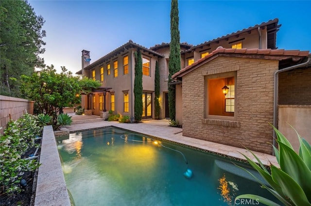 21 Land Bird, Irvine, CA 92618 - back of house at dusk featuring a chimney, a tiled roof, and stucco siding
