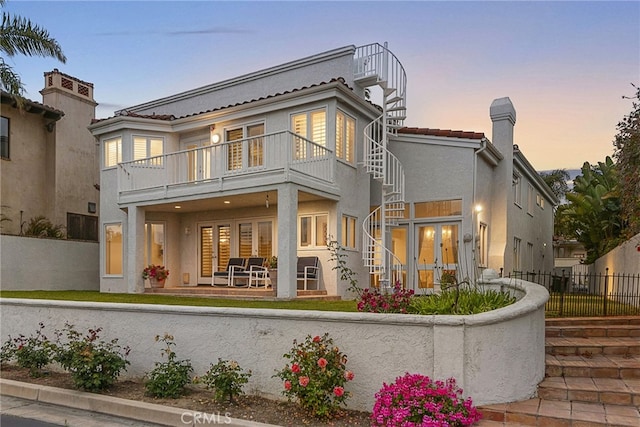 4026 Calle Lisa, San Clemente, CA 92672 - back of house at dusk with a balcony, french doors, stucco siding, a chimney, and a tiled roof