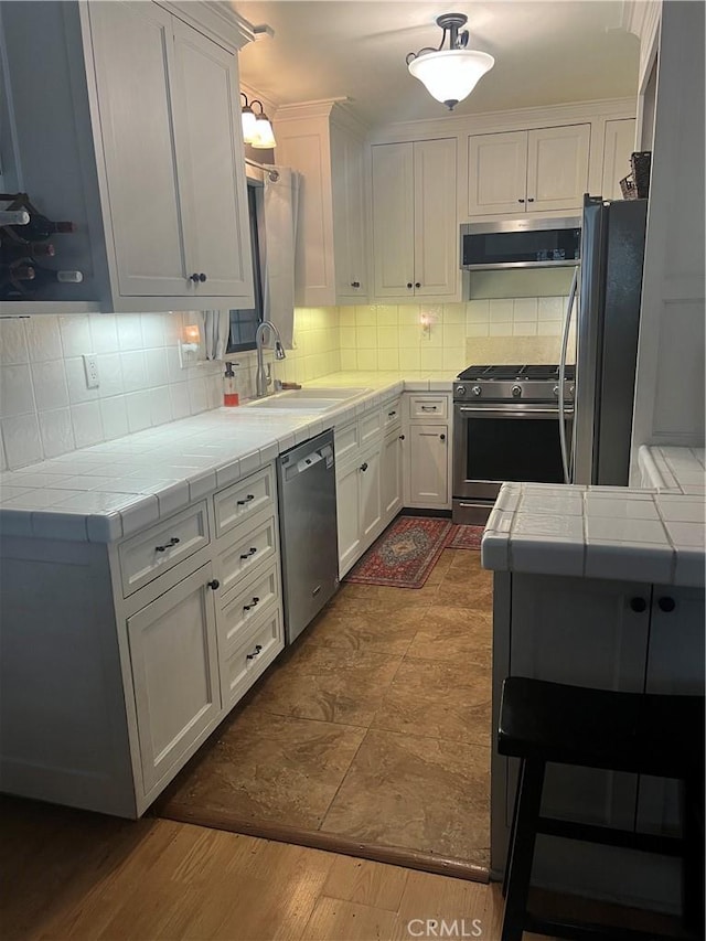 5726 Lodgepole Dr, Wrightwood, CA 92397 - kitchen with stainless steel appliances, tile countertops, a sink, ventilation hood, and backsplash