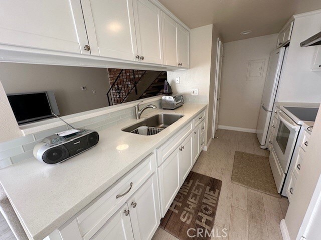 2070 Avenida Placida Unit 3, Simi Valley, CA 93063 - kitchen featuring a sink, white appliances, white cabinetry, and light wood-type flooring