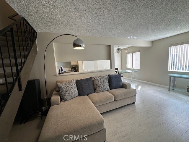 2070 Avenida Placida Unit 3, Simi Valley, CA 93063 - living room featuring stairway, a textured ceiling, baseboards, and wood finished floors