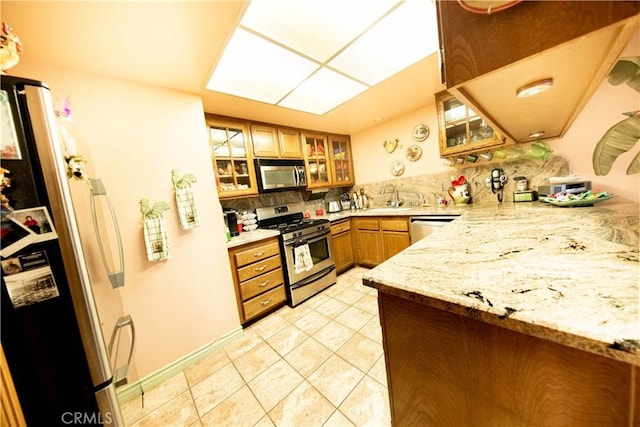 1921 Pine Dr, La Habra, CA 90631 - kitchen with appliances with stainless steel finishes, brown cabinets, light tile patterned floors, backsplash, and glass insert cabinets