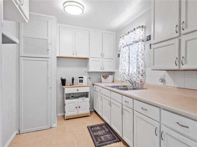 1040 Flora St, Barstow, CA 92311 - kitchen featuring a sink, white cabinets, light countertops, light tile patterned floors, and tasteful backsplash