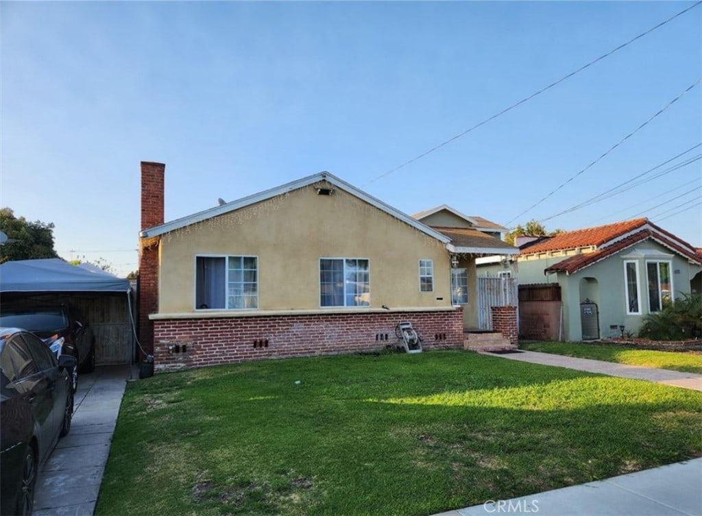 4007 Cudahy St, Huntington Park, CA 90255 - bungalow-style house featuring stucco siding, a front lawn, a chimney, and brick siding