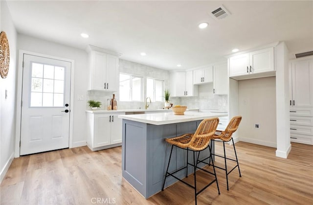 16417 Ivy Ave, Fontana, CA 92335 - kitchen with backsplash, white cabinetry, a kitchen island, a kitchen breakfast bar, and baseboards