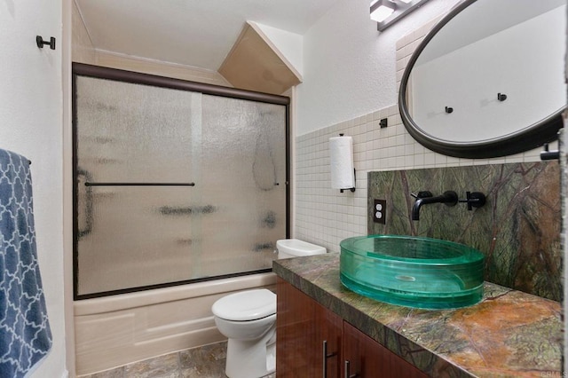 6919 Sandleford Way, San Diego, CA 92139 - bathroom featuring toilet, vanity, combined bath / shower with glass door, tile walls, and stone finish floors