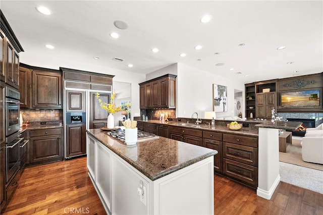 3016 Milagro Way, Fullerton, CA 92835 - kitchen with appliances with stainless steel finishes, a sink, a kitchen island, dark brown cabinetry, and a peninsula
