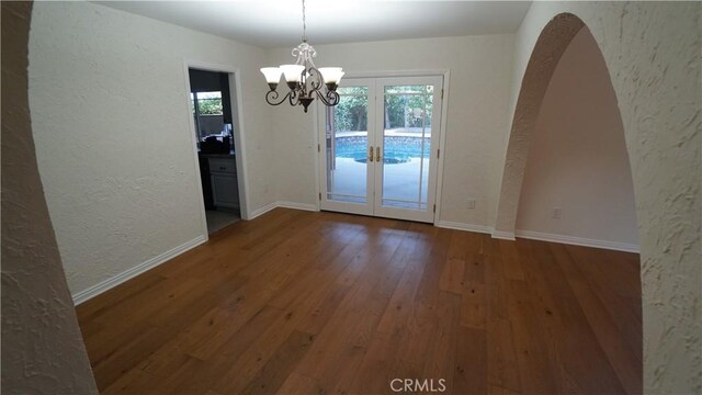 24530 Breckenridge Pl, Newhall, CA 91321 - unfurnished dining area featuring a textured wall, french doors, arched walkways, a chandelier, and wood-type flooring
