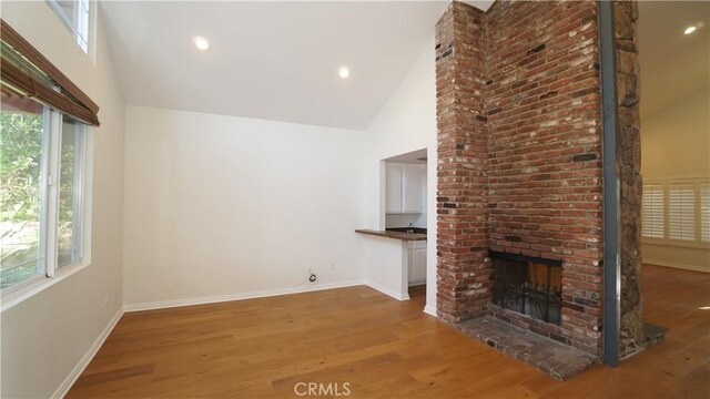 24530 Breckenridge Pl, Newhall, CA 91321 - unfurnished living room with high vaulted ceiling, wood finished floors, baseboards, a brick fireplace, and recessed lighting