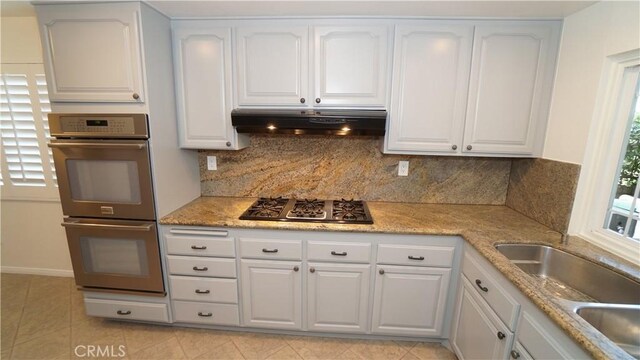 24530 Breckenridge Pl, Newhall, CA 91321 - kitchen featuring stainless steel appliances, under cabinet range hood, white cabinetry, backsplash, and light tile patterned flooring