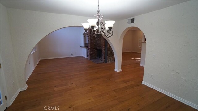 24530 Breckenridge Pl, Newhall, CA 91321 - unfurnished dining area featuring arched walkways, a chandelier, wood finished floors, and a textured wall