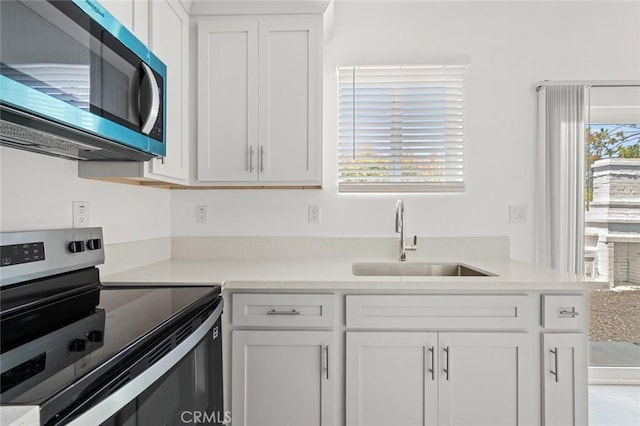 2101 W 76th St, Los Angeles, CA 90047 - kitchen with appliances with stainless steel finishes, a sink, white cabinets, and light countertops