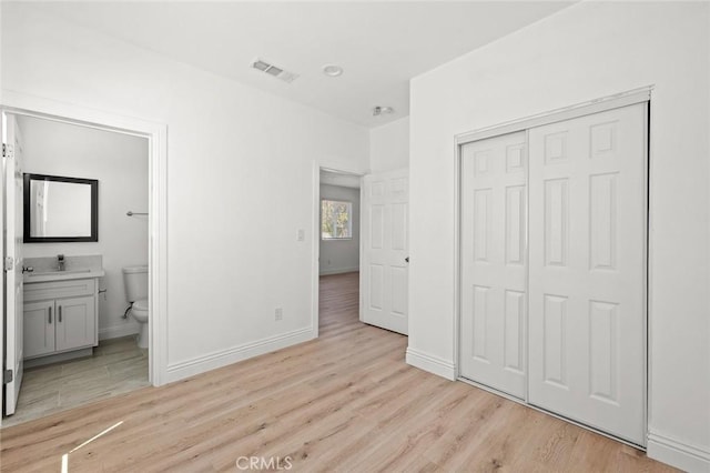 2101 W 76th St, Los Angeles, CA 90047 - unfurnished bedroom featuring light wood-style floors, a closet, baseboards, a sink, and ensuite bathroom
