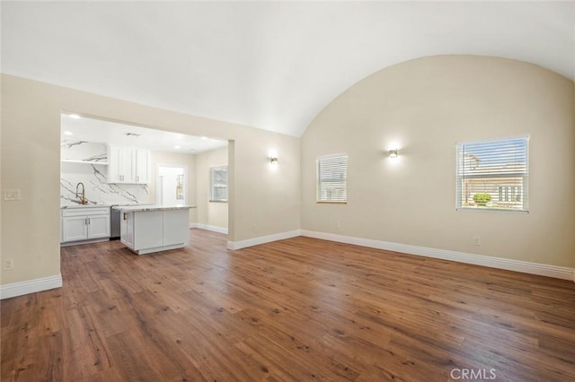 2101 W 76th St, Los Angeles, CA 90047 - unfurnished living room with vaulted ceiling, healthy amount of natural light, a sink, wood finished floors, and baseboards