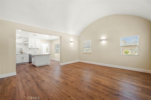 2101 W 76th St, Los Angeles, CA 90047 - unfurnished living room with plenty of natural light, vaulted ceiling, and wood finished floors