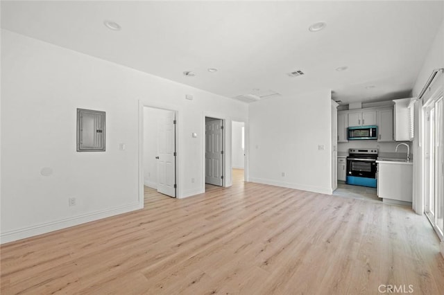 2101 W 76th St, Los Angeles, CA 90047 - unfurnished living room featuring electric panel, light wood-type flooring, baseboards, a sink, and recessed lighting