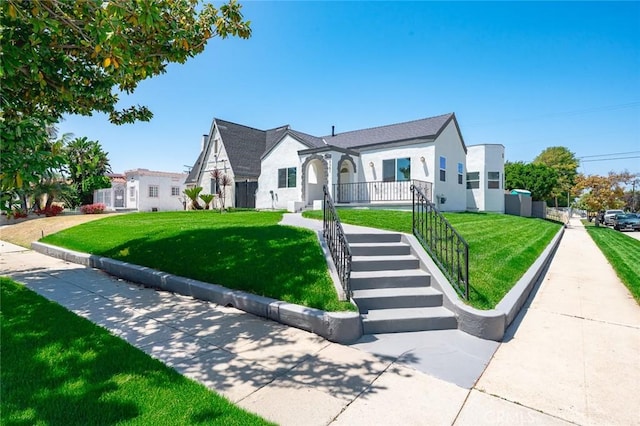 2101 W 76th St, Los Angeles, CA 90047 - tudor house with a front lawn, stairway, and stucco siding