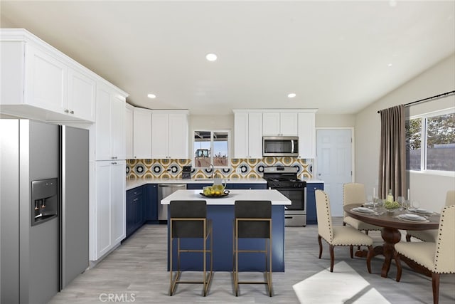 5951 Rose Ellen Ave Unit 29, Palms, CA 92277 - kitchen featuring appliances with stainless steel finishes, decorative backsplash, white cabinets, light countertops, and a kitchen island