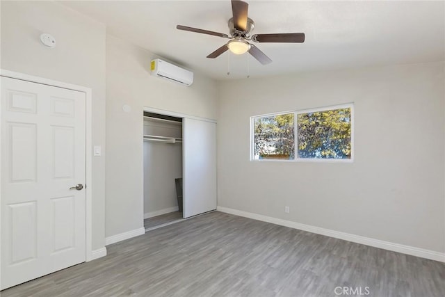 5951 Rose Ellen Ave Unit 29, Palms, CA 92277 - unfurnished bedroom with a wall unit AC, wood finished floors, a closet, and baseboards