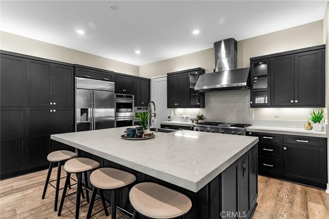 62 Pelican Ln, Irvine, CA 92618 - kitchen with wall chimney exhaust hood, stainless steel appliances, dark cabinets, a sink, and a kitchen breakfast bar