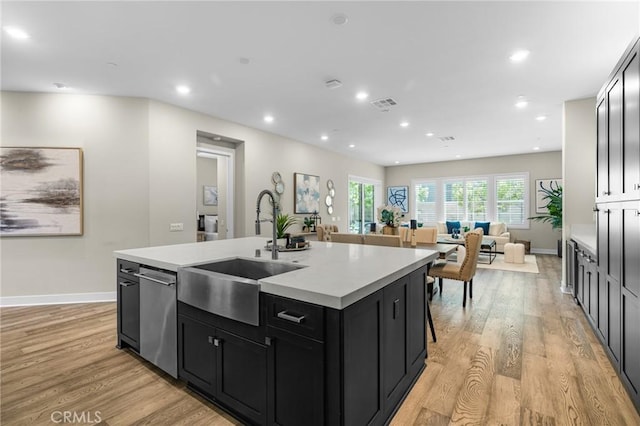 62 Pelican Ln, Irvine, CA 92618 - kitchen with a sink, dark cabinetry, a kitchen island with sink, light countertops, and light wood finished floors