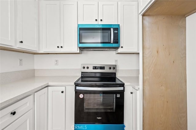 939 E 97th St, Los Angeles, CA 90002 - kitchen with stainless steel microwave, electric stove, white cabinetry, and light countertops