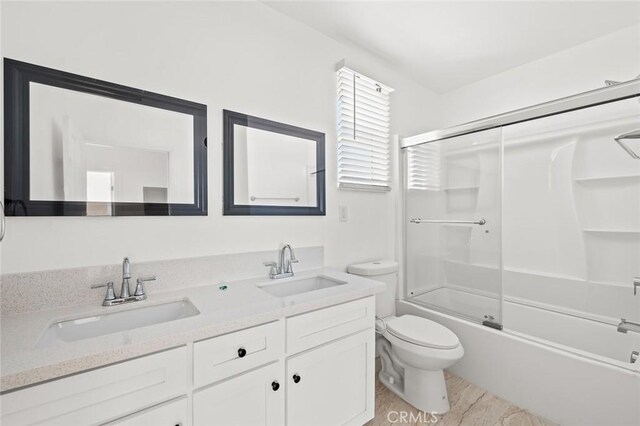 939 E 97th St, Los Angeles, CA 90002 - bathroom featuring toilet, double vanity, and bath / shower combo with glass door