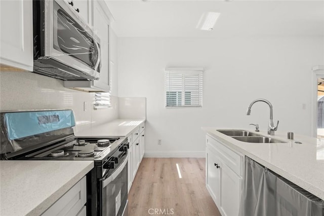 939 E 97th St, Los Angeles, CA 90002 - kitchen with appliances with stainless steel finishes, a sink, light wood finished floors, and white cabinetry
