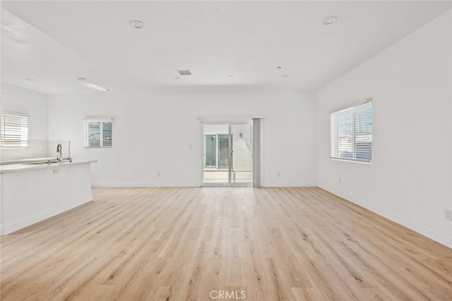 939 E 97th St, Los Angeles, CA 90002 - unfurnished living room with healthy amount of natural light, light wood-type flooring, a sink, and baseboards