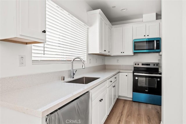 939 E 97th St, Los Angeles, CA 90002 - kitchen featuring electric stove, a sink, stainless steel dishwasher, white cabinetry, and light wood finished floors