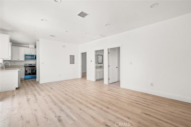 939 E 97th St, Los Angeles, CA 90002 - unfurnished living room featuring electric panel, light wood finished floors, a sink, baseboards, and recessed lighting