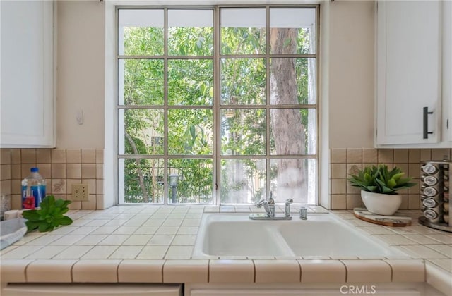 1375 Kelton Ave Unit 104, Los Angeles, CA 90024 - kitchen featuring tile counters, a sink, backsplash, and white cabinets