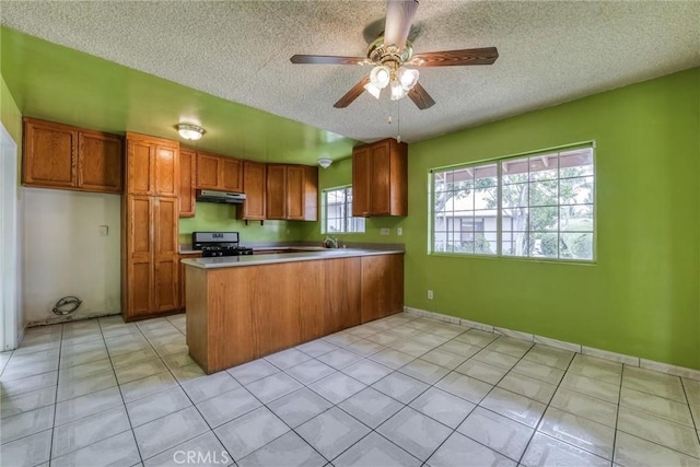 17415 Minnehaha St, Granada Hills, CA 91344 - kitchen featuring range with gas cooktop, a peninsula, brown cabinetry, a textured ceiling, and under cabinet range hood