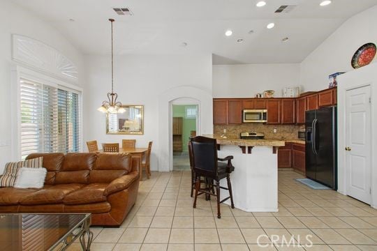 4516 Streamport Dr, Riverside, CA 92505 - kitchen with stainless steel microwave, black fridge, light tile patterned floors, a breakfast bar, and decorative backsplash
