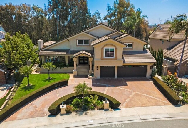 27773 Hidden Trail Rd, Laguna Hills, CA 92653 - view of front facade featuring a garage, stucco siding, curved driveway, a chimney, and a front lawn